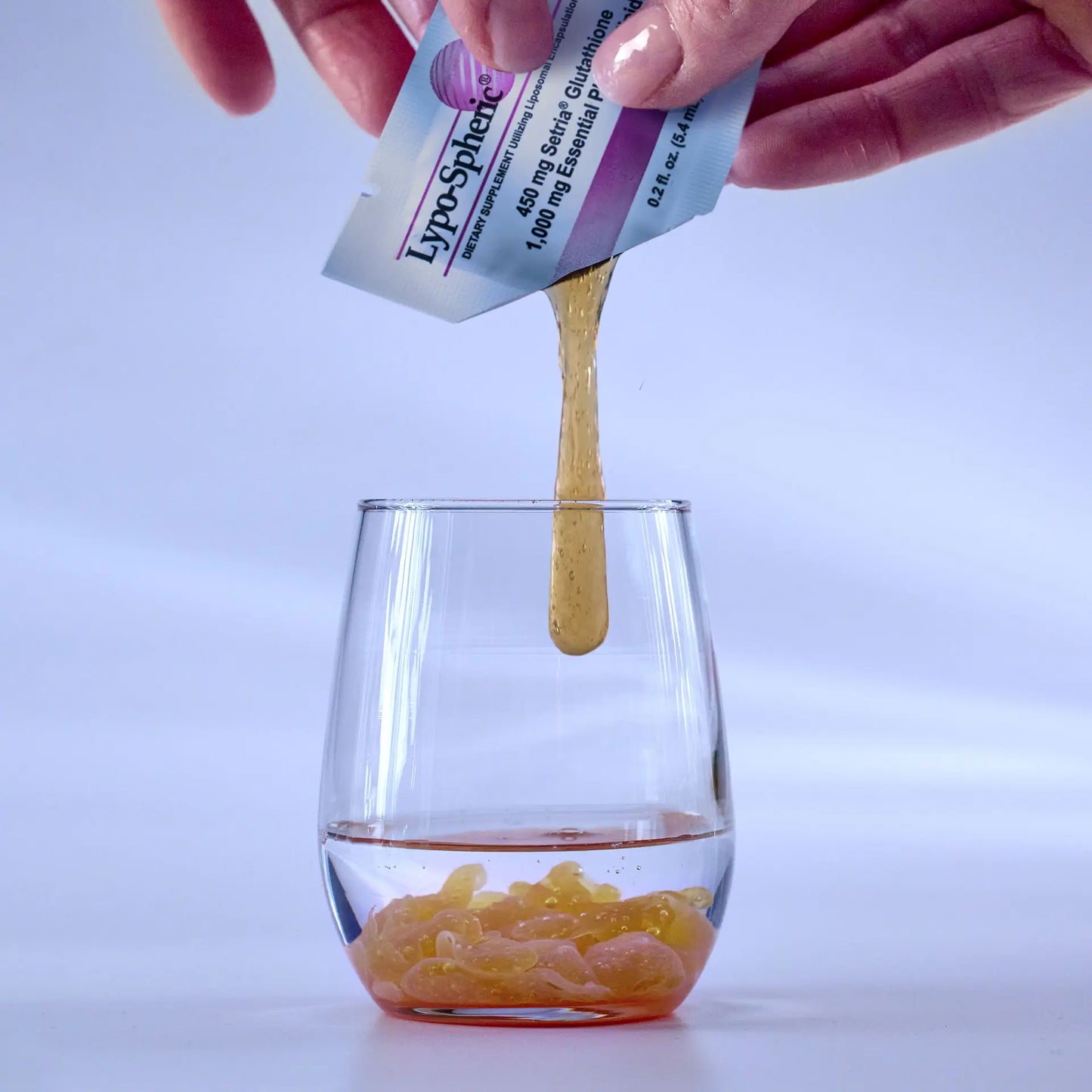 hand squeezing Lypo-Spheric® Glutathione into a shot glass